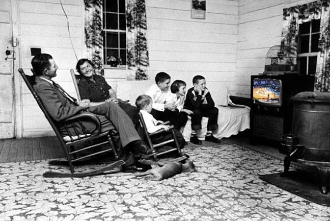 A family watching television in a living room

Description automatically generated