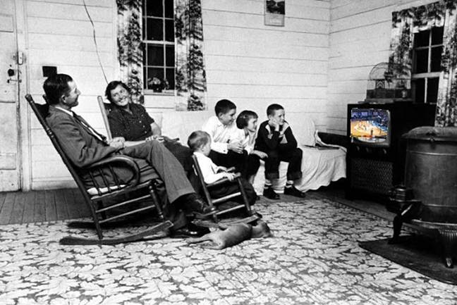 A family watching television in a living room

Description automatically generated